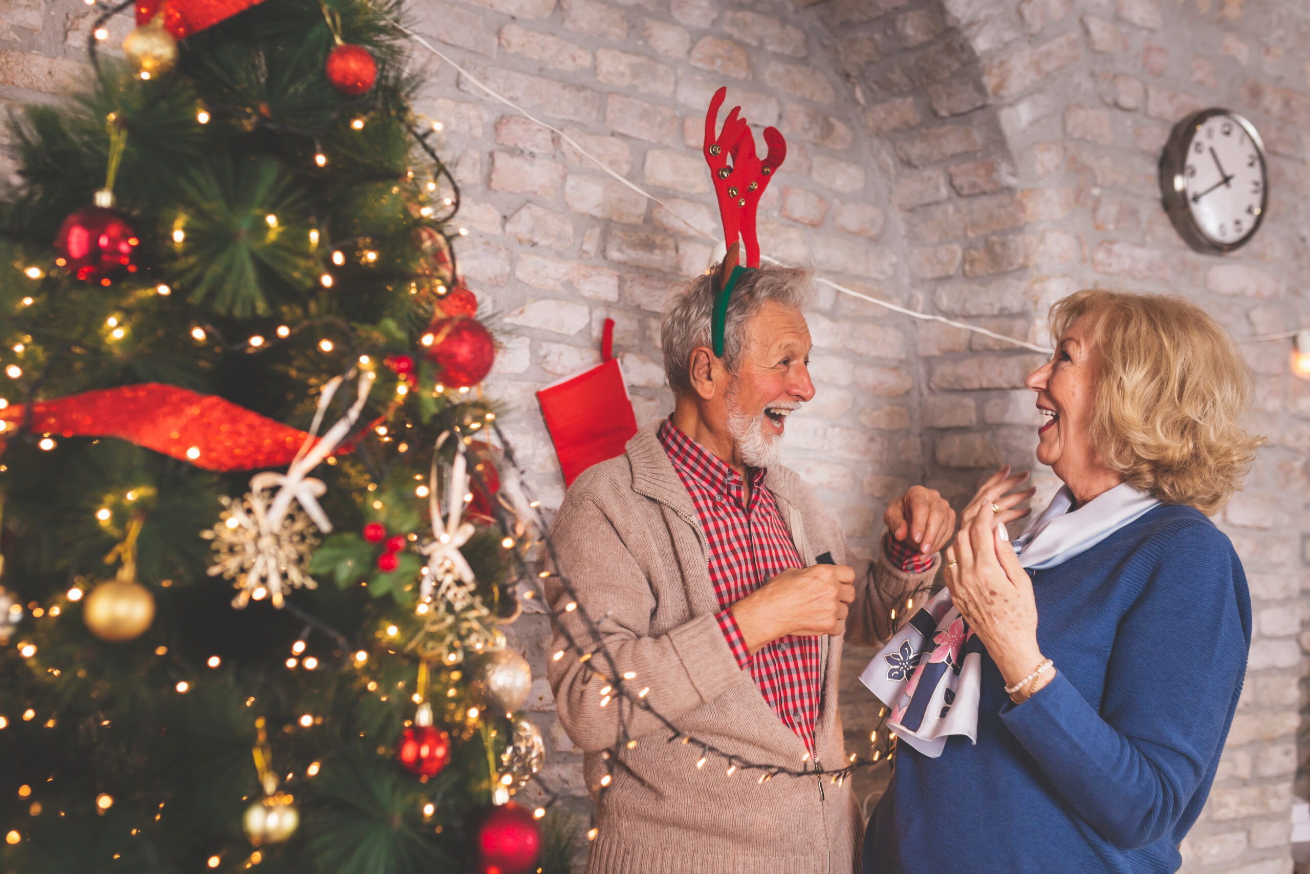 Senior couple placing Christmas lights to Christmas tree