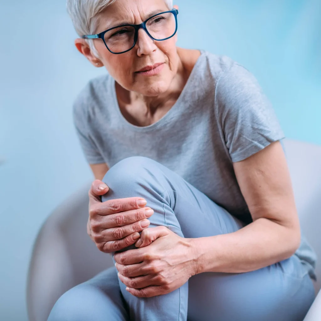 seniorka trzymająca się z bólu za kolano